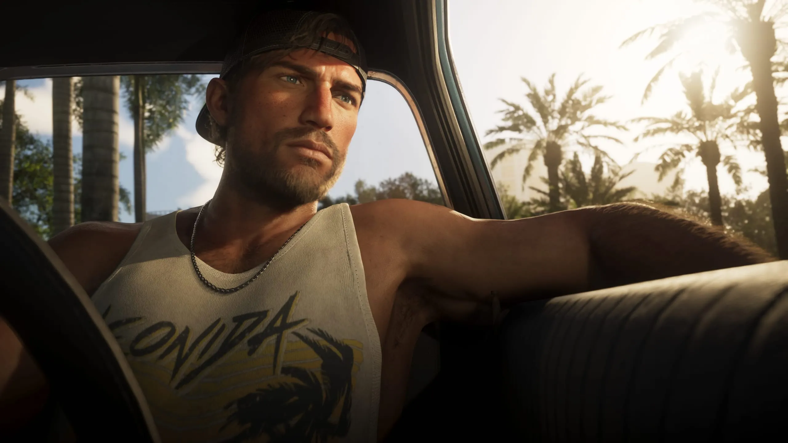 Man in a backwards cap behind the wheel, Leonida tank top, sunlit palms outside