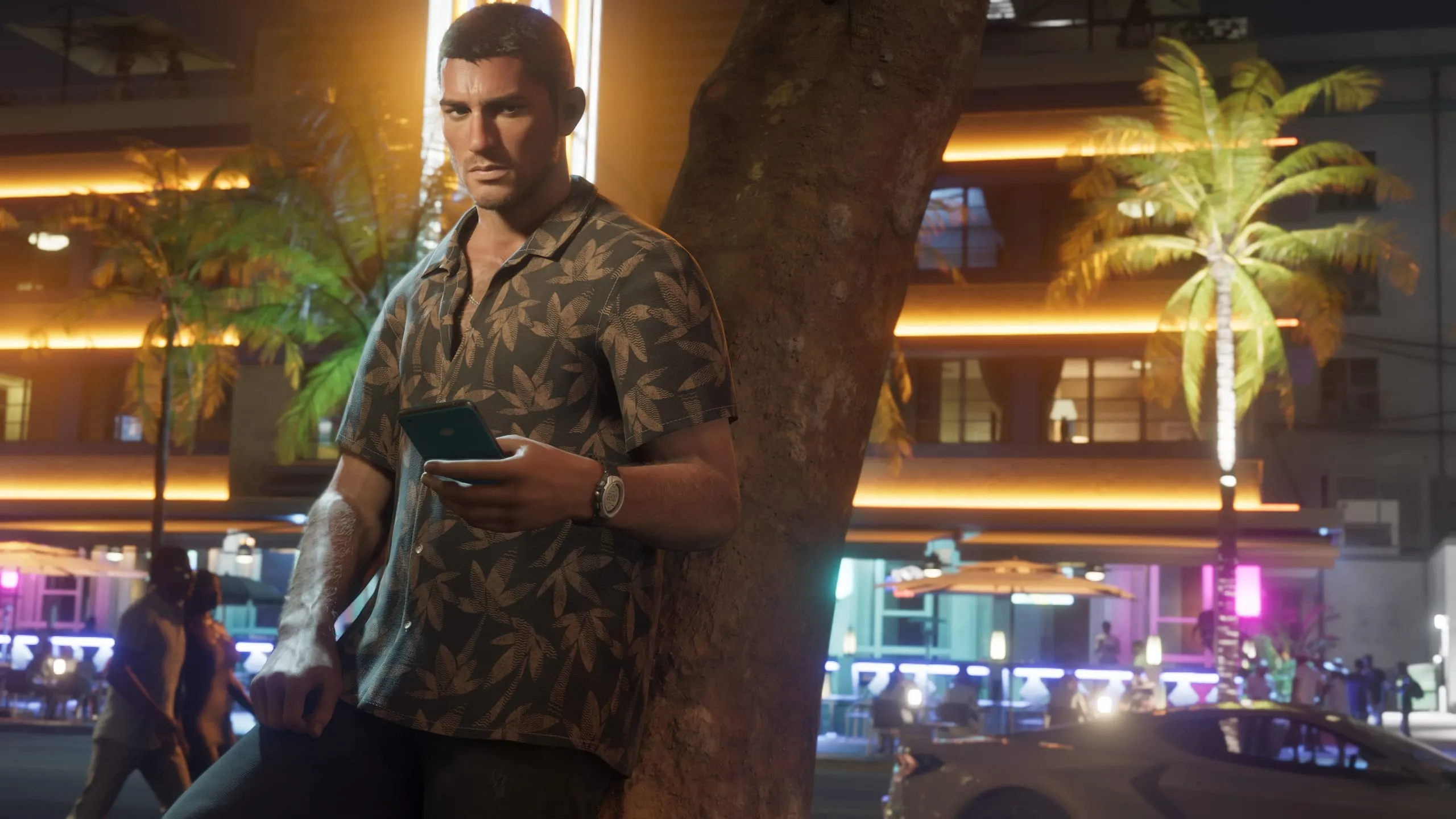 Man checking his phone at night, a neon-lit hotel strip glowing behind him