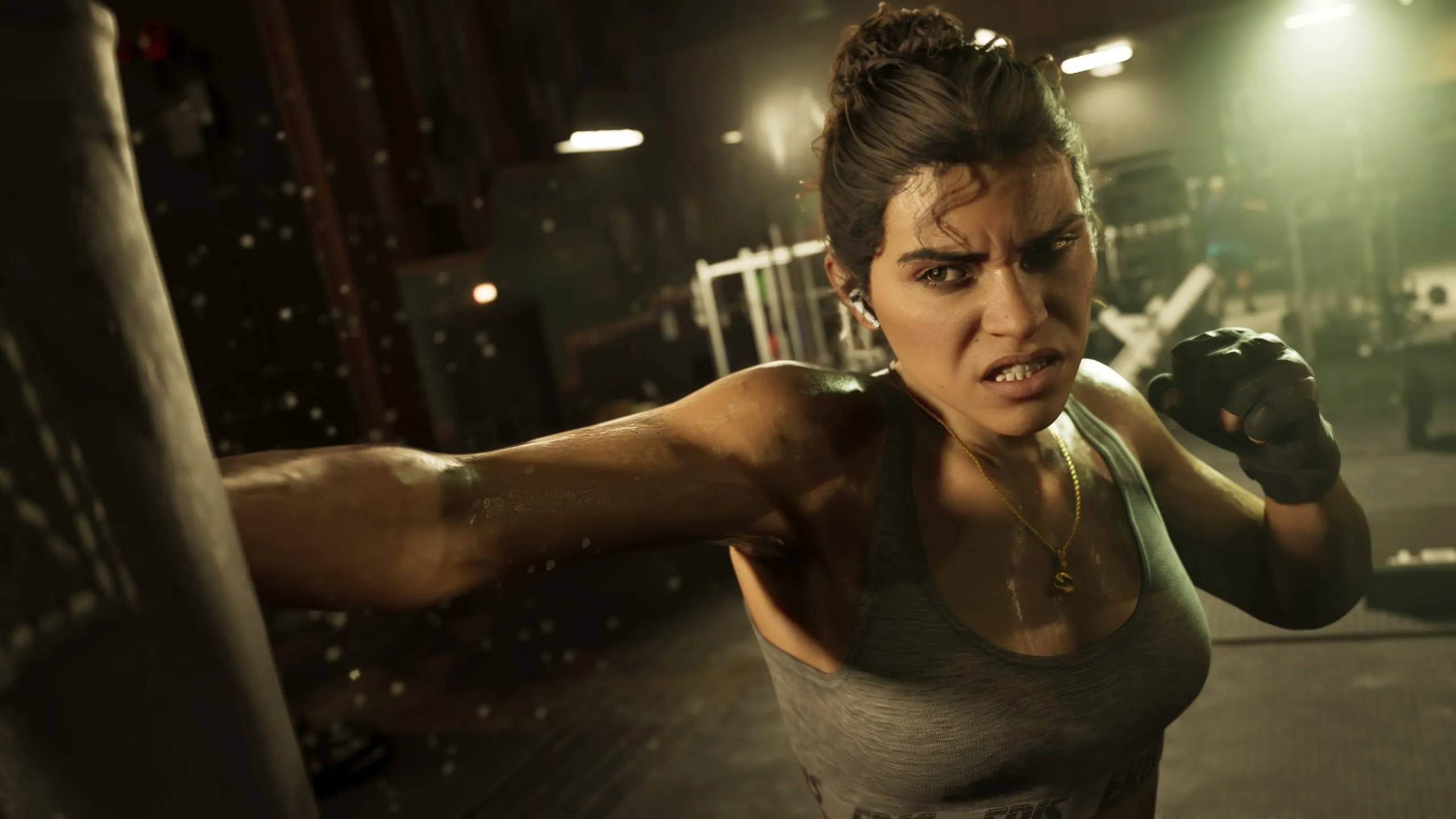 Young woman in a sports bra throwing a punch at a heavy bag in a dim gym